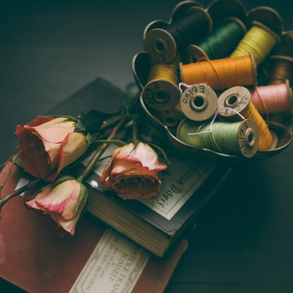 Atelier still life: dried roses, books and spools of thread