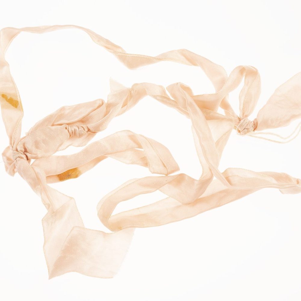 A pale pink satin ribbon on a white background