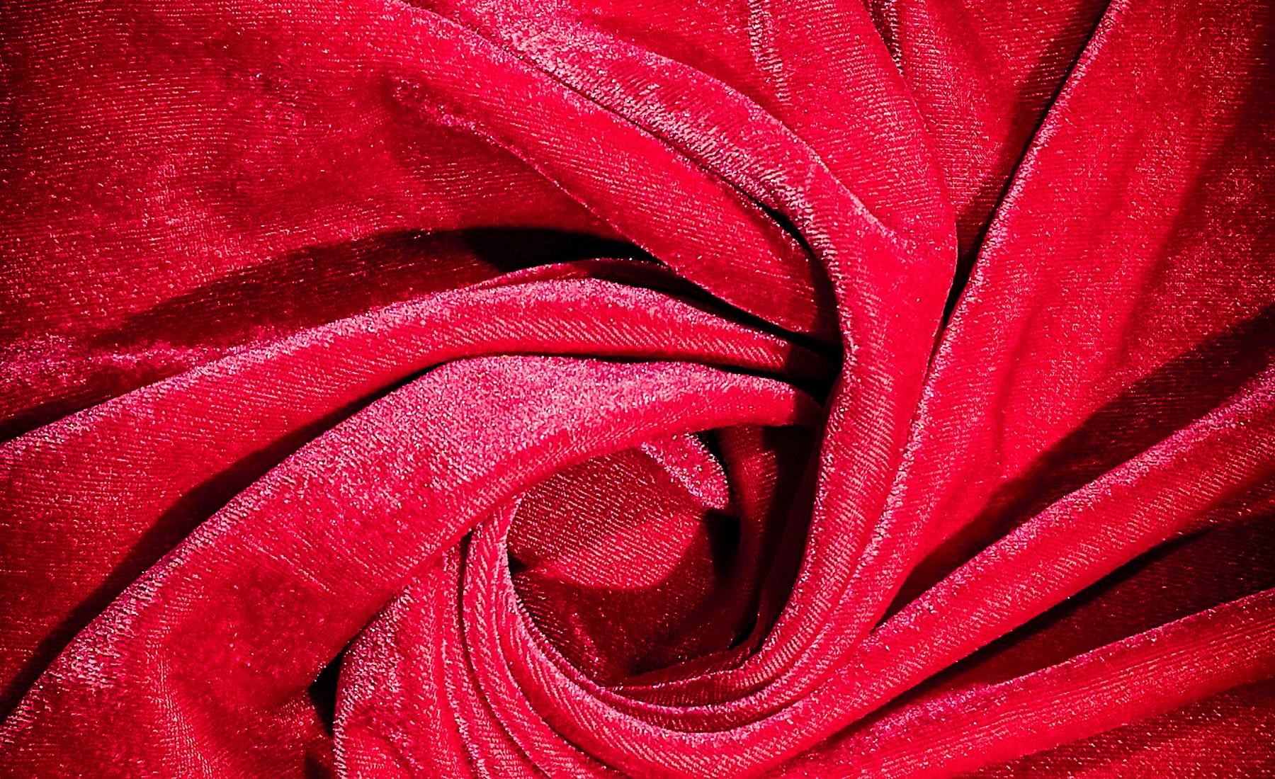 Swirling folds and highlights in deep crimson velvet